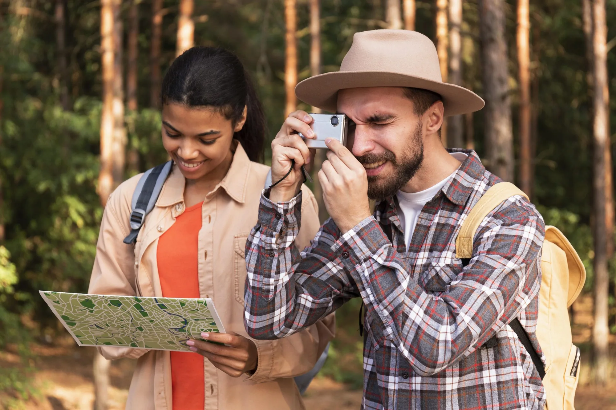 Couple with a camera and a map walking through a forest