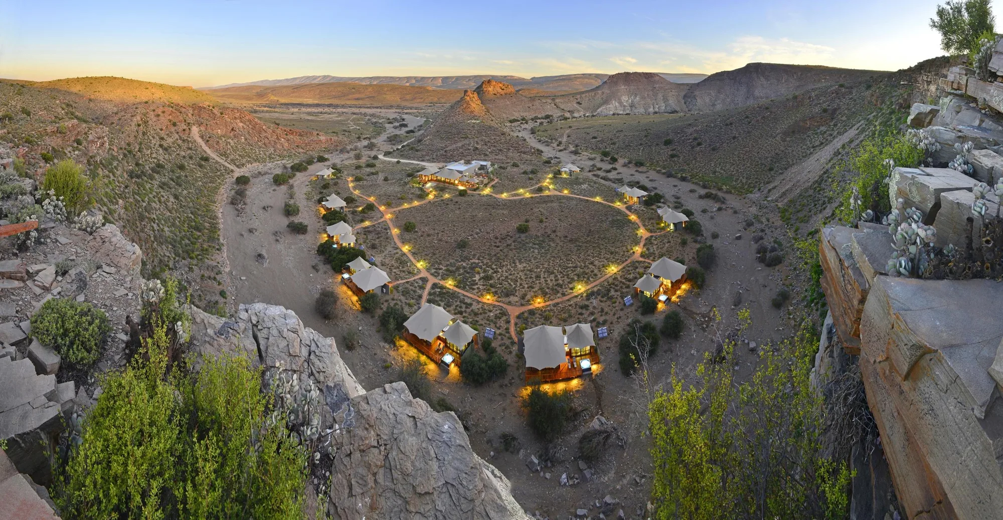 Aerial view of a tented safari lodge at dusk in the Sanbona Wildlife Reserve, with mountains behind