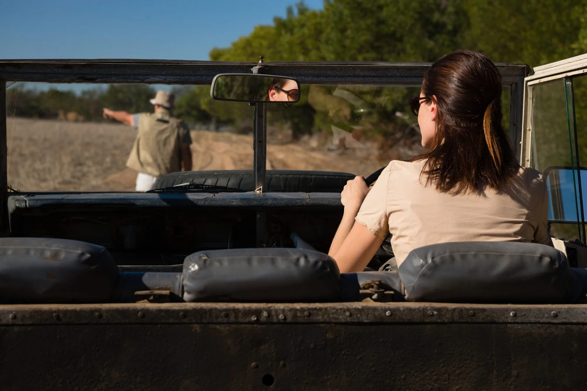 Guest in an open safari vehicle listening to her guide