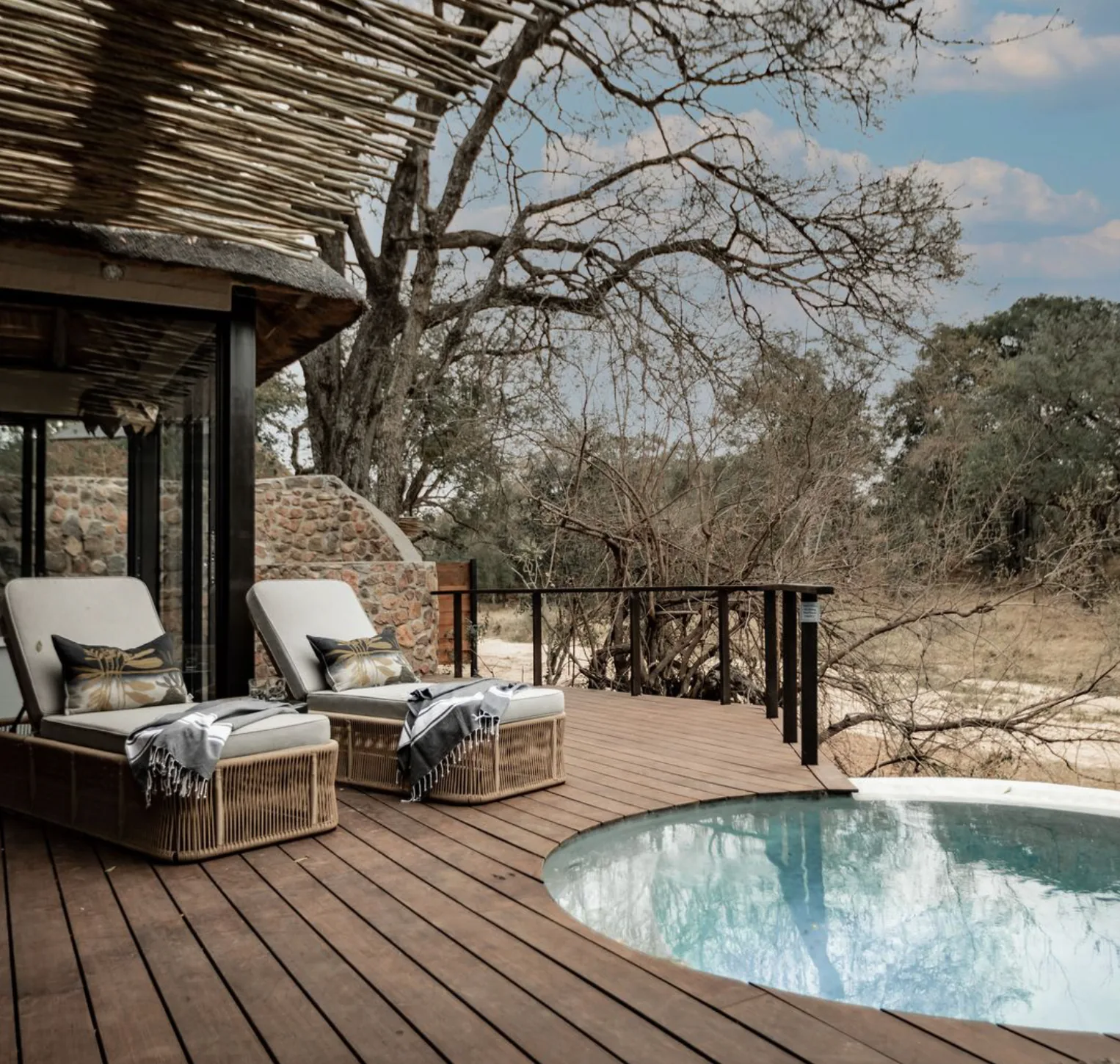 Private plunge pool and two loungers on a wooden lodge deck under the trees